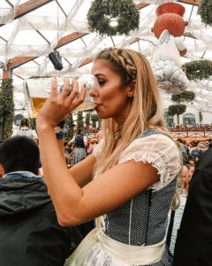 Girl chugging beer in dirndle at Oktoberfest