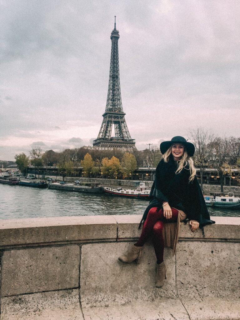 Girl sitting by the water overlooking the Eiffel Tower in Paris, France